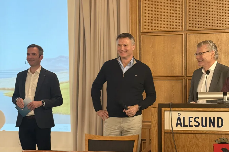 Tre menn som står foran et podium