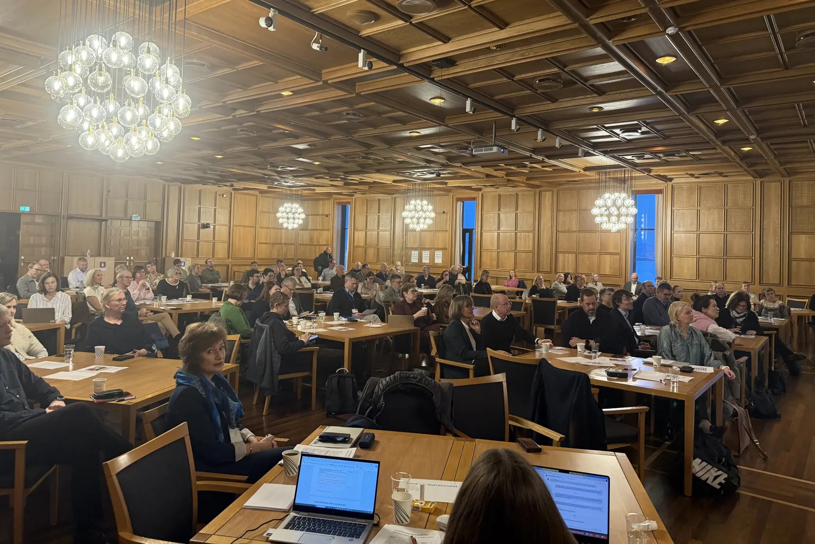 Konferansesal med over 100 deltagere rundt mange bord.