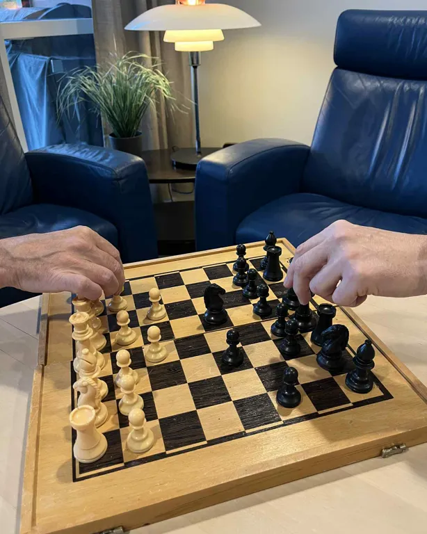 Et sjakkbrett med brikker på og to skinnstoler