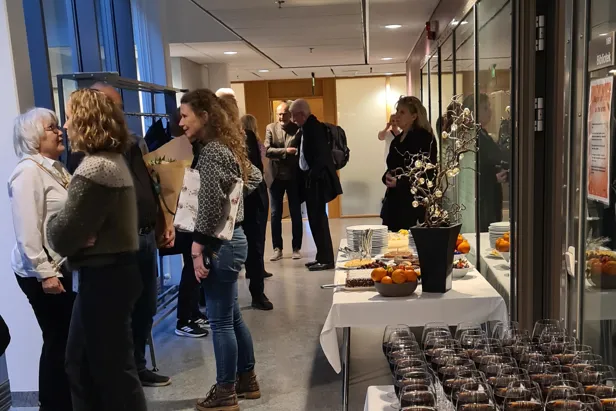 En gruppe mennesker som står i et rom med bord og stoler