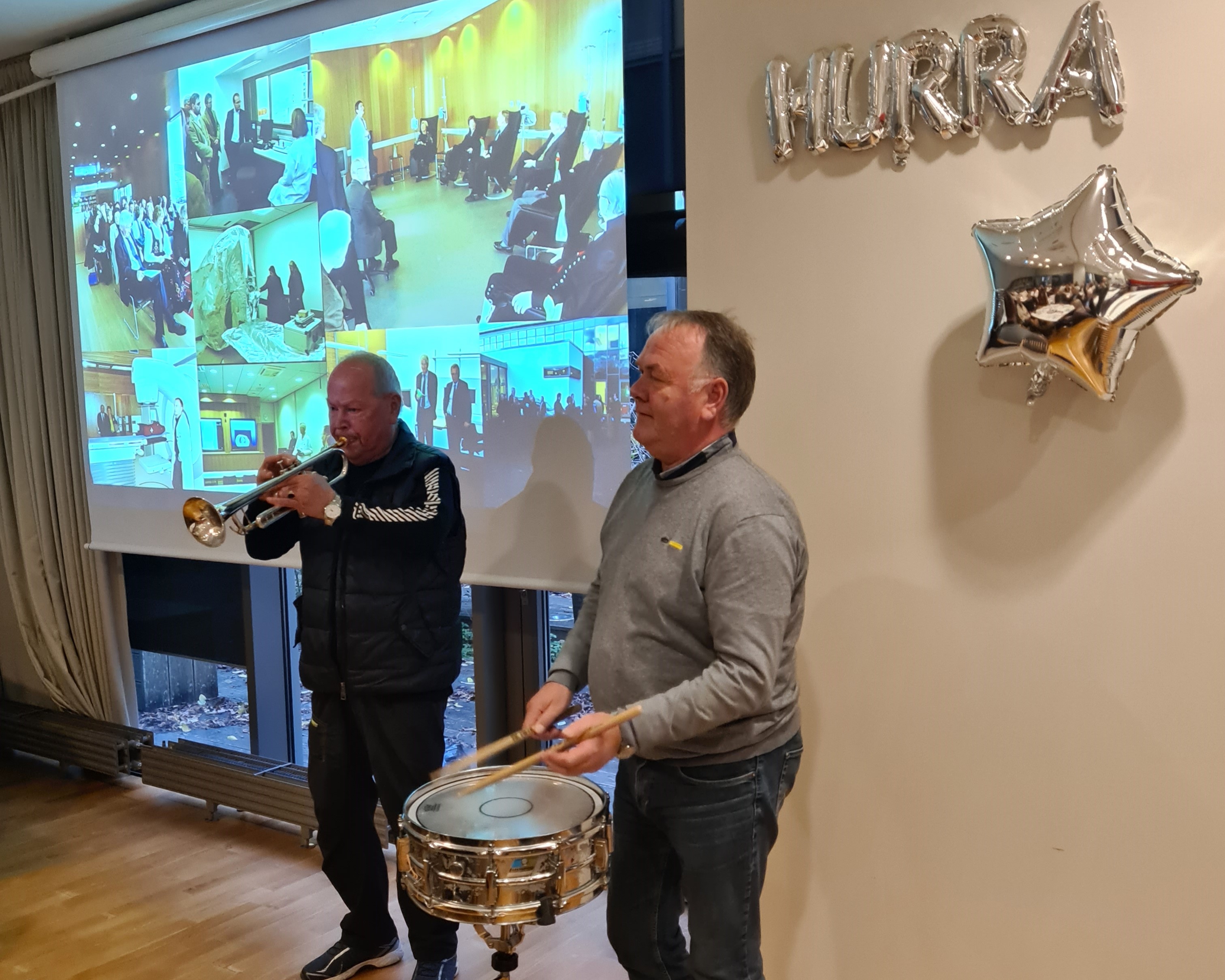 En mann som spiller et musikkinstrument ved siden av en mann som spiller trommer