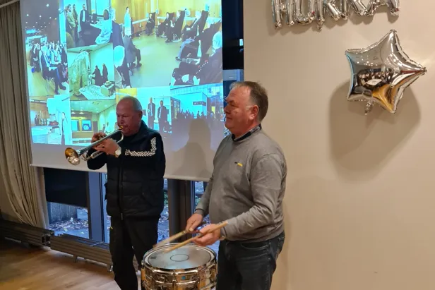 En mann som spiller et musikkinstrument ved siden av en mann som spiller trommer