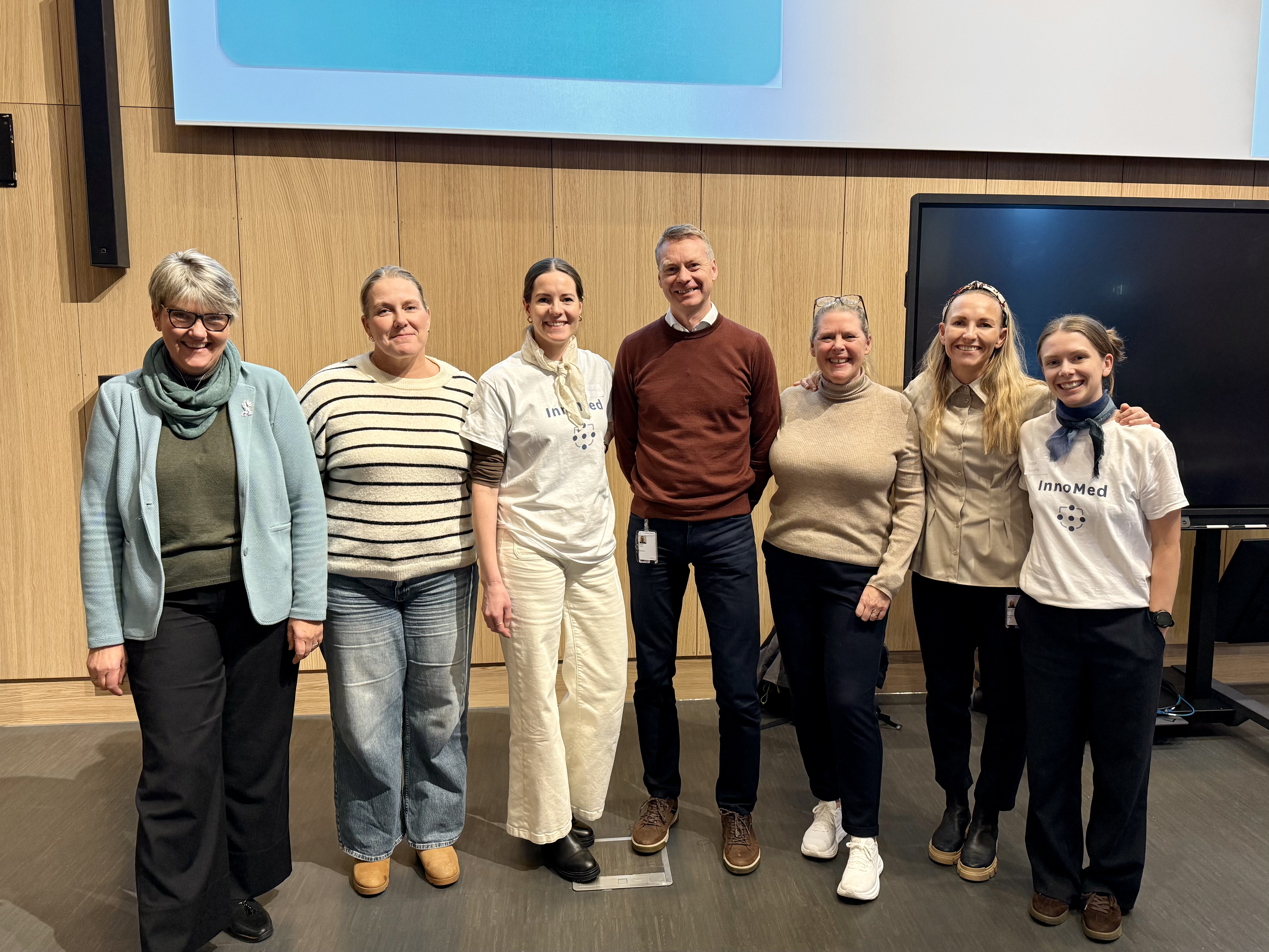 Prosjektgruppa for SamOpp står oppstilt og smiler til kameraet inne på konferansesalen.