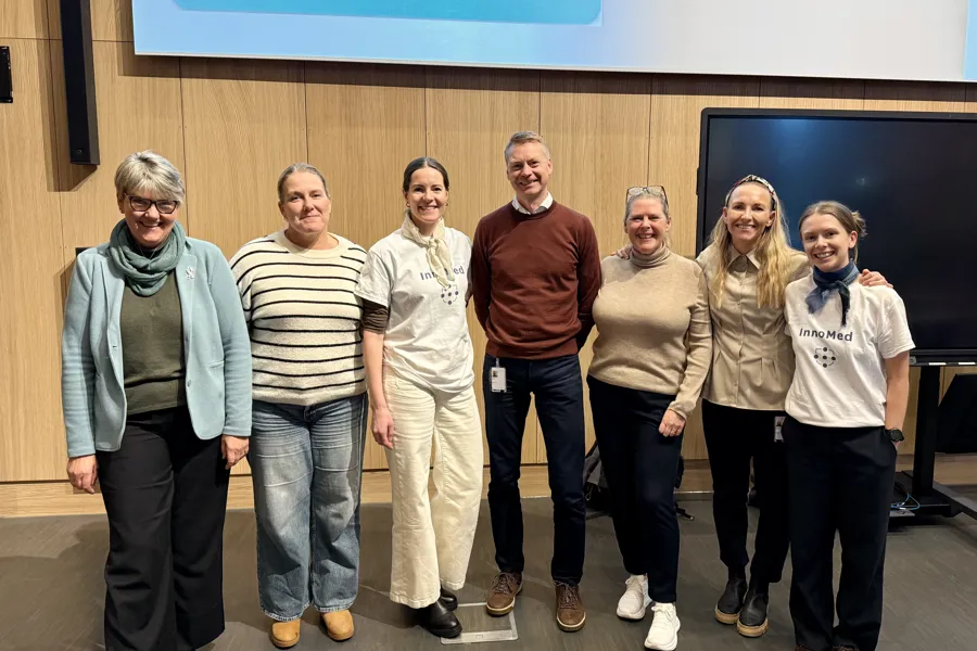 Prosjektgruppa for SamOpp står oppstilt og smiler til kameraet inne på konferansesalen.
