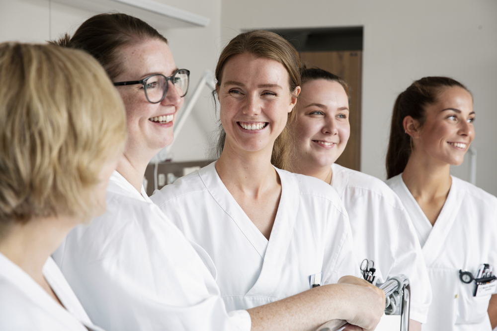 Nært bilde av flire smilande tilsette i sjukehusmiljø