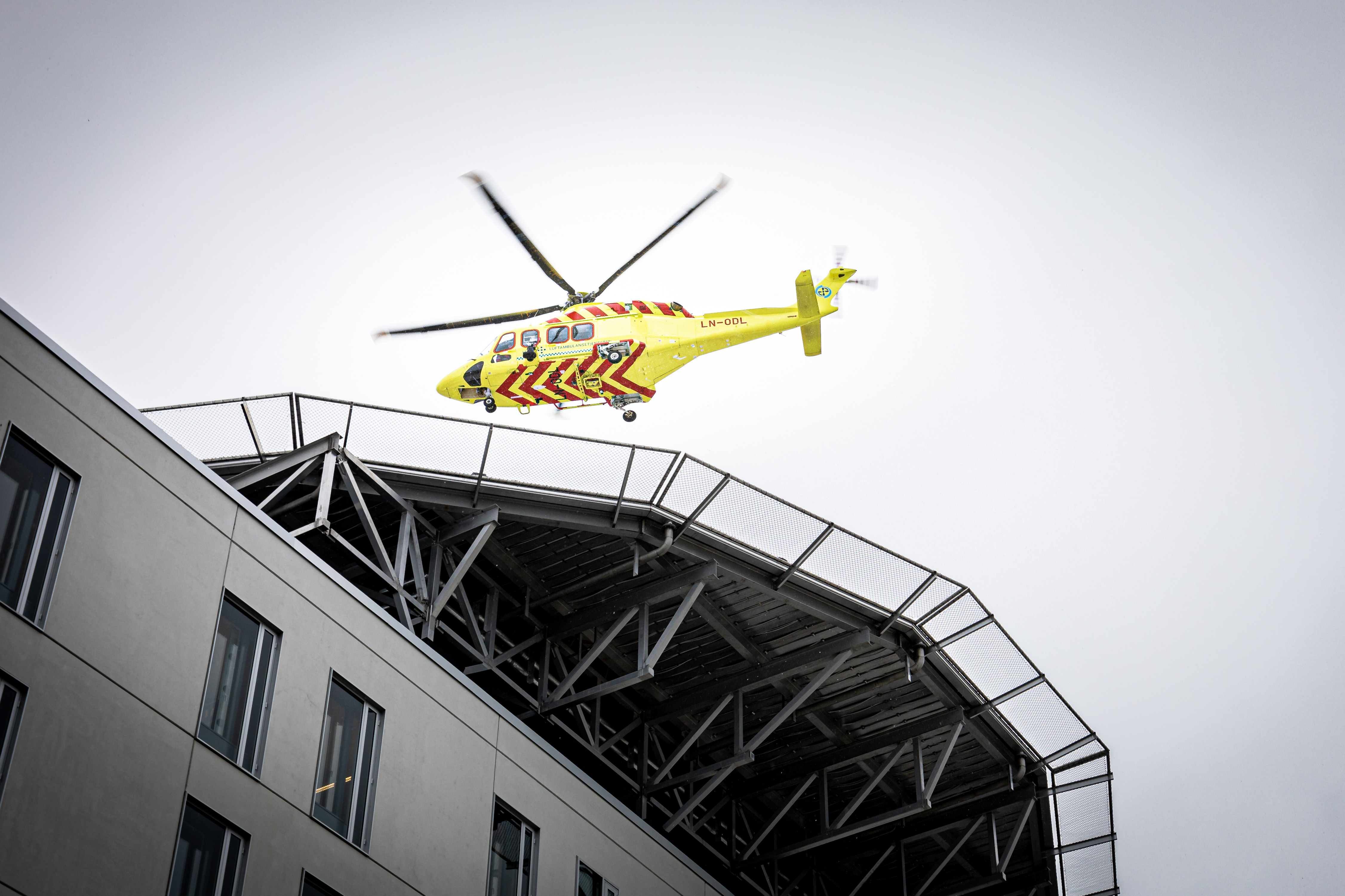 Et gult og blått helikopter som flyr over en bygning
